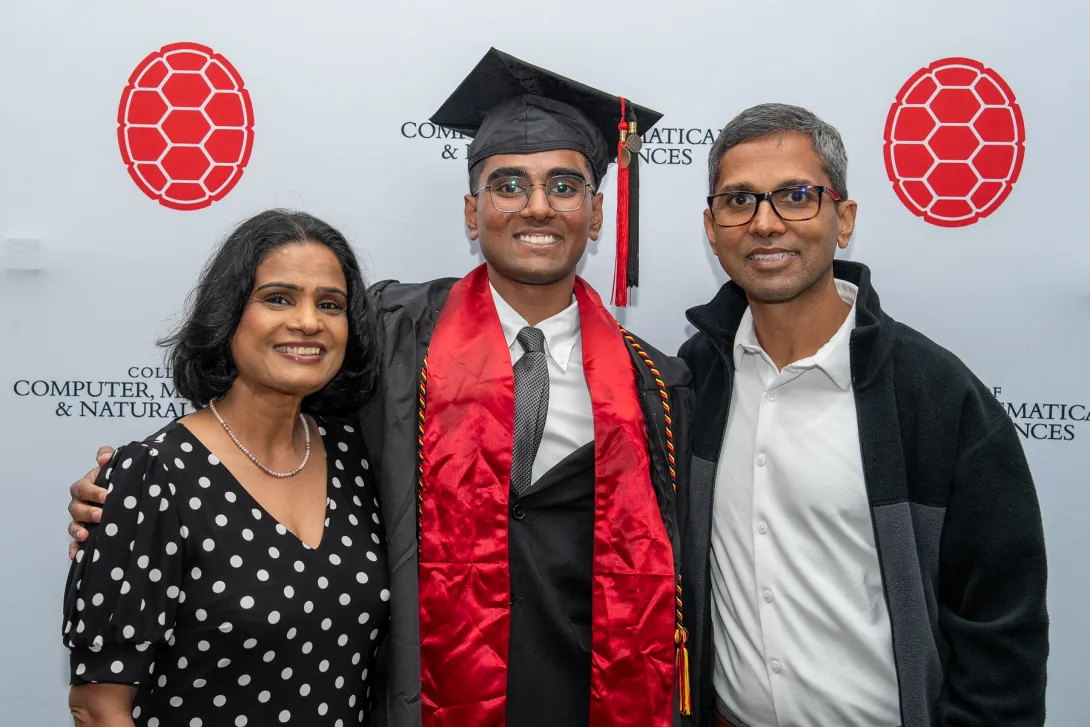 Graduate stands between two family members
