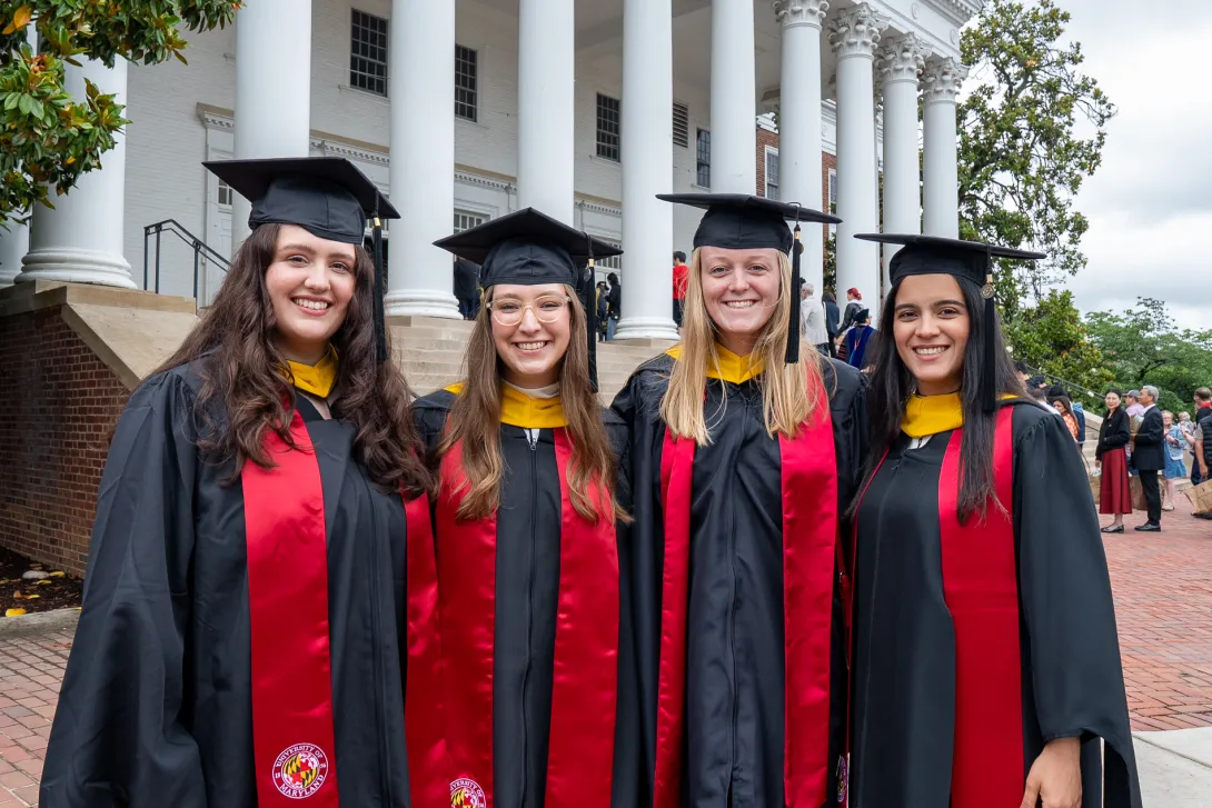 Group of four graduates stand outside of the Reckord Armory