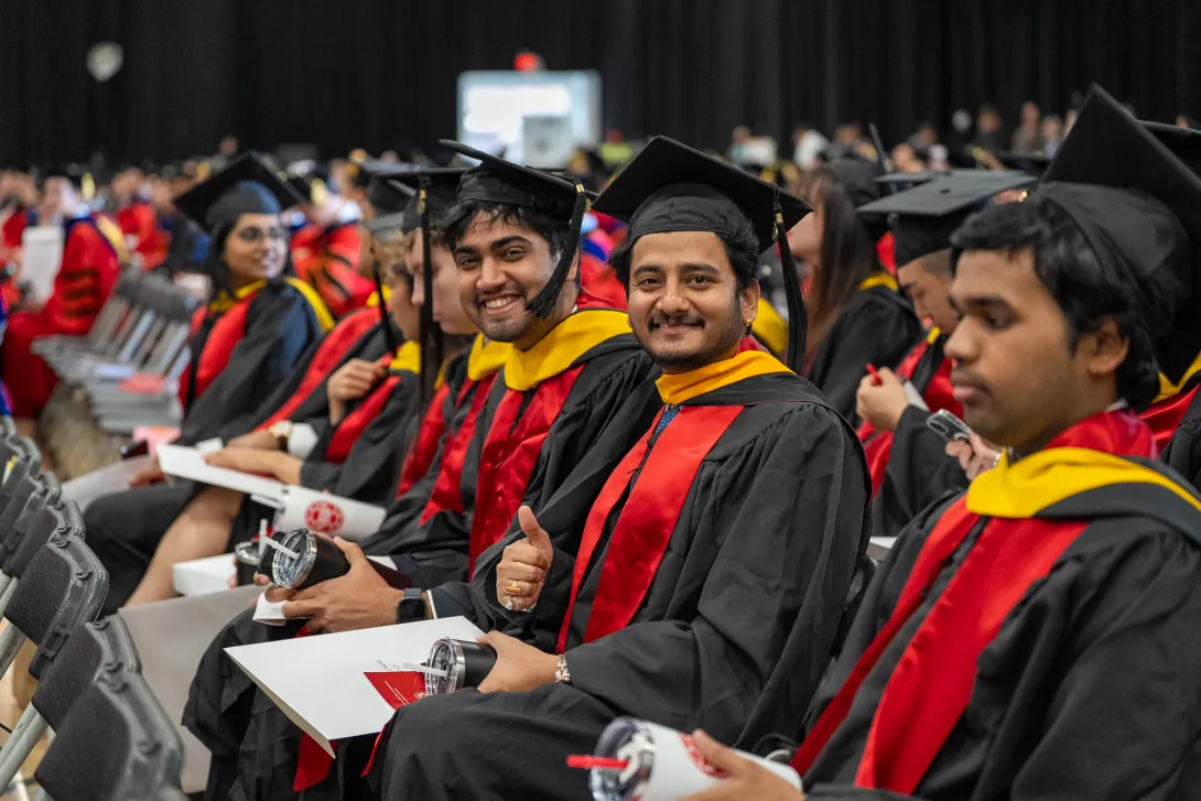 Graduates seated and smiling in the audience during commencement